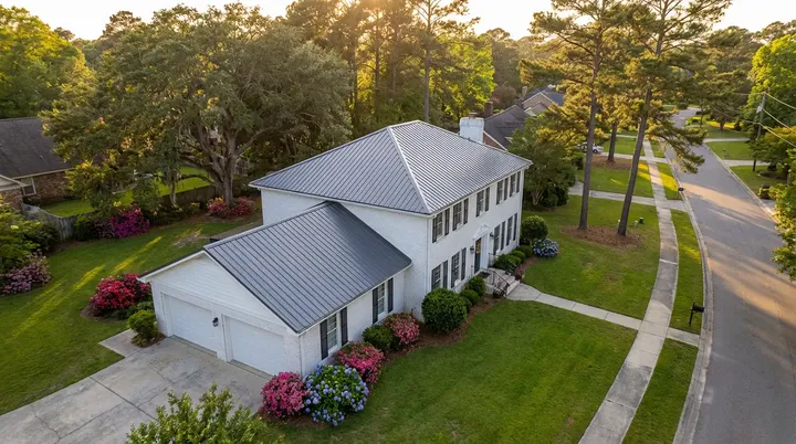 A dark gray metal roof on a white two-story house with an attached garage