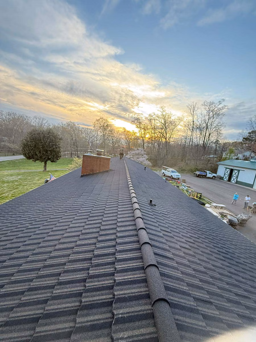 Ridge line of a gray stone-coated steel roof at sunset